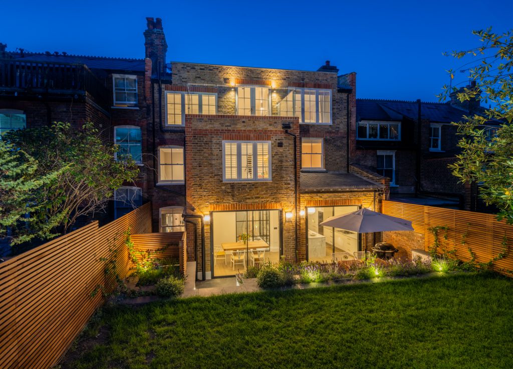 Muswell Haven rear elevation, landscaped garden and glazing at dusk
